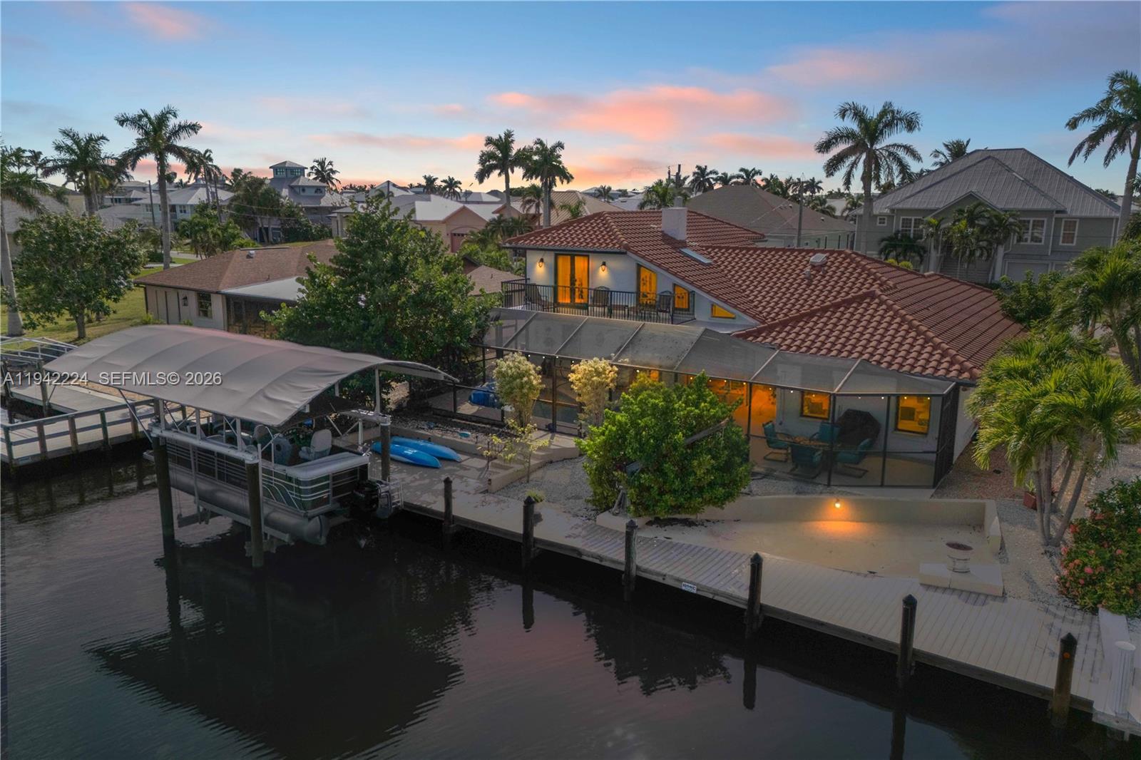 An aerial view shows a waterfront house with a tiled roof, boat lift, and dock — OTHER CITY - IN THE STATE OF FLORIDA, FL