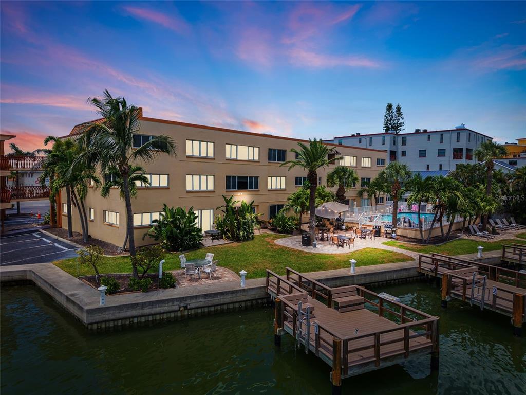 An aerial view shows a coastal apartment complex situated between a waterway and the beach — 10265 GULF BOULEVARD UNIT A-301, ST PETERSBURG, FL