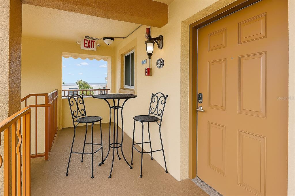 A living room with hardwood floors, a gray sofa, and an open kitchen area — 10265 GULF BOULEVARD UNIT A-301, ST PETERSBURG, FL