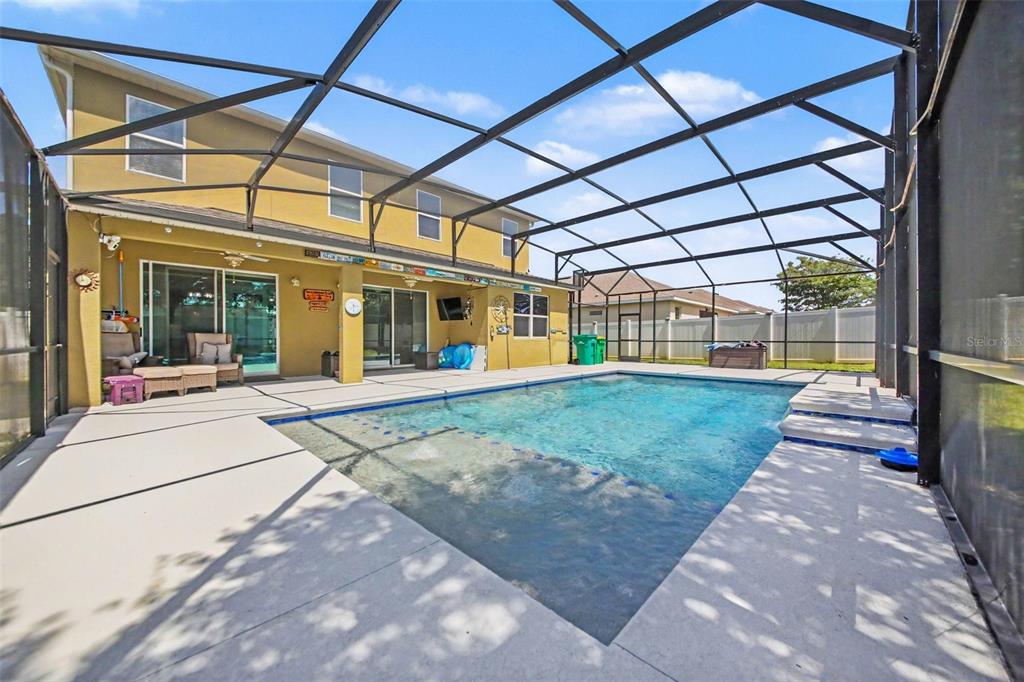 A swimming pool sits on a concrete patio enclosed by a large black screen cage — 1374 MERION DRIVE, MOUNT DORA, FL