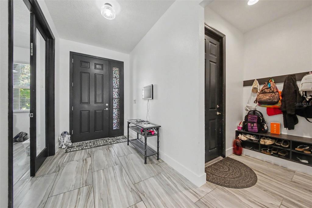 An entryway features a black front door, tiled floors, a console table, and a mudroom bench — 1374 MERION DRIVE, MOUNT DORA, FL