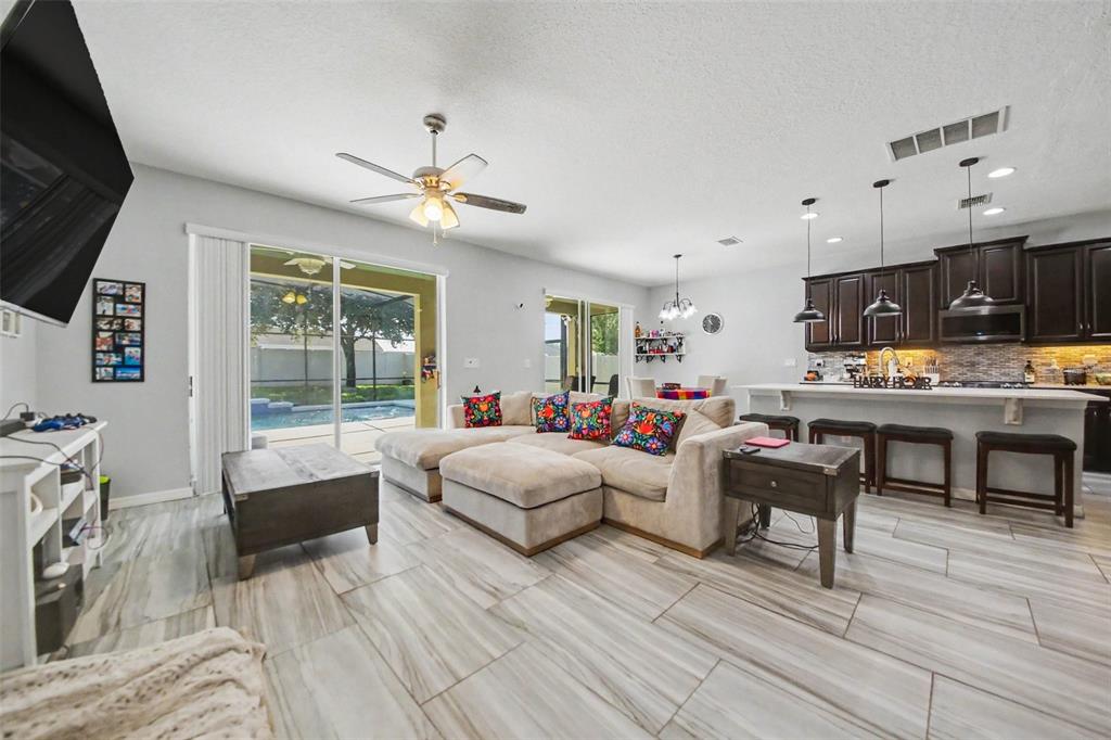 An open-concept living room and kitchen featuring light tile floors and a view of a pool — 1374 MERION DRIVE, MOUNT DORA, FL