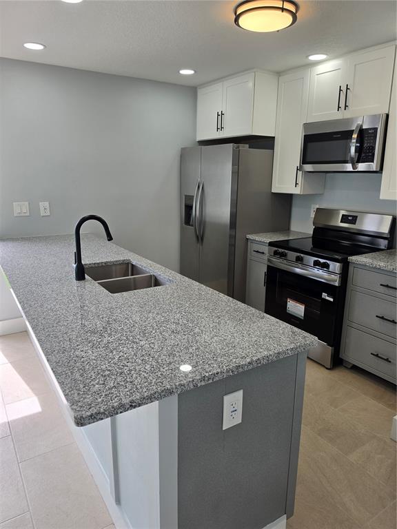 A kitchen features a granite-topped island, stainless steel appliances, and white and gray cabinetry — 145 131ST AVENUE E UNIT 3, ST PETERSBURG, FL