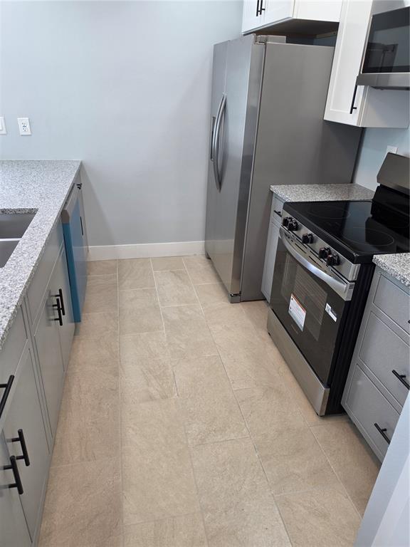 A kitchen features gray cabinets, granite countertops, stainless steel appliances, and light-colored tile flooring — 145 131ST AVENUE E UNIT 3, ST PETERSBURG, FL