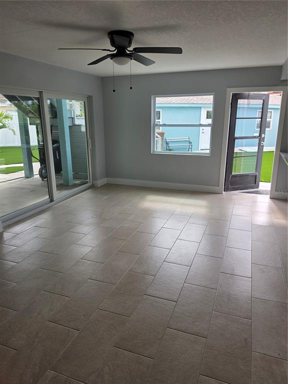 A room with light gray walls, tile flooring, a ceiling fan, sliding doors, and a door — 145 131ST AVENUE E UNIT 3, ST PETERSBURG, FL
