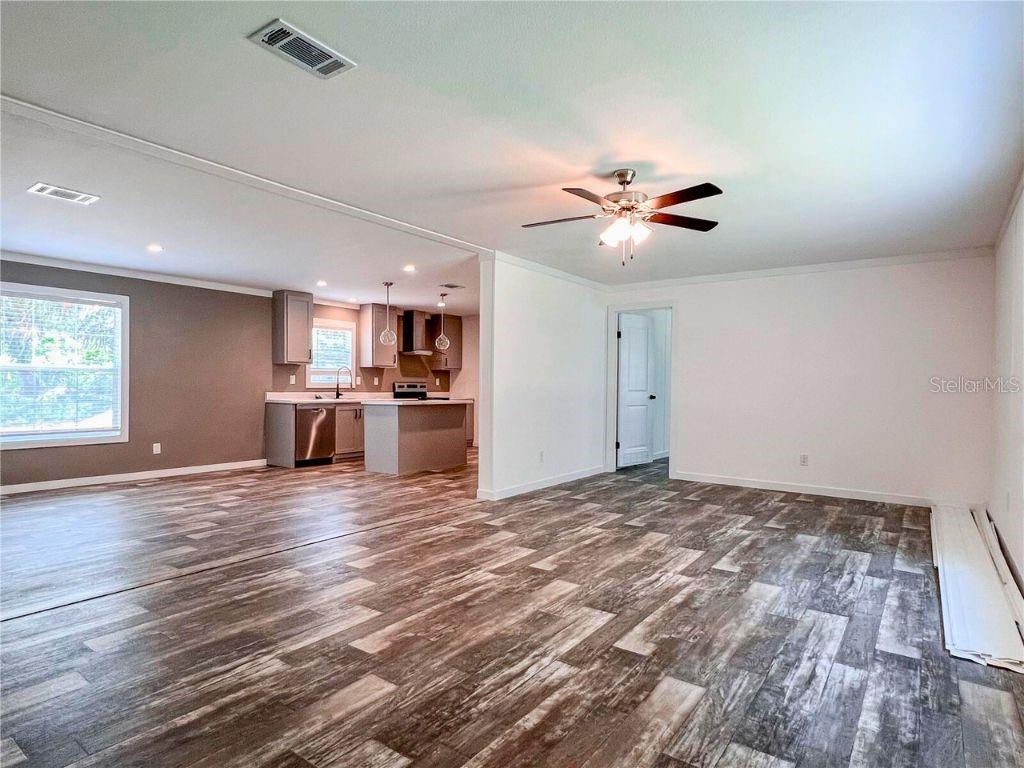 A living room with wood-look flooring opens into a kitchen with gray cabinets — 16108 GUPTON STREET, BROOKSVILLE, FL