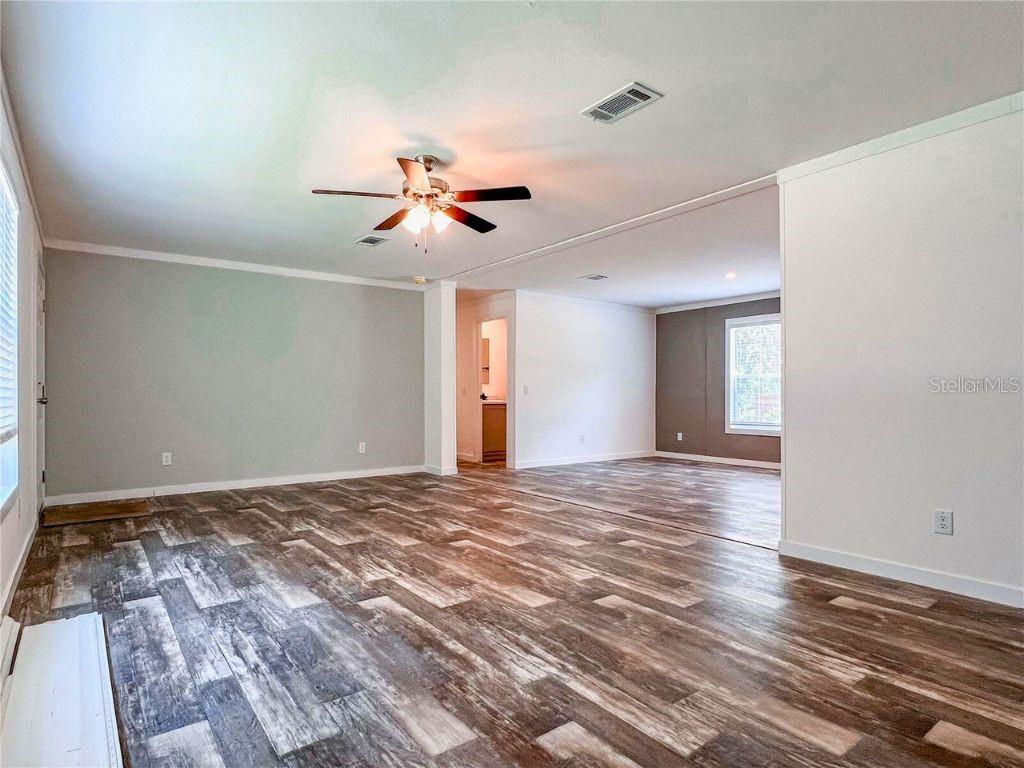An open-concept living area features wood-look flooring, light gray walls, and a ceiling fan — 16108 GUPTON STREET, BROOKSVILLE, FL