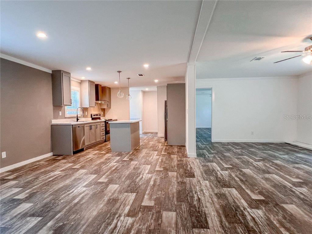 A kitchen with grey cabinets and an island opens into a living area with wood-look flooring — 16108 GUPTON STREET, BROOKSVILLE, FL
