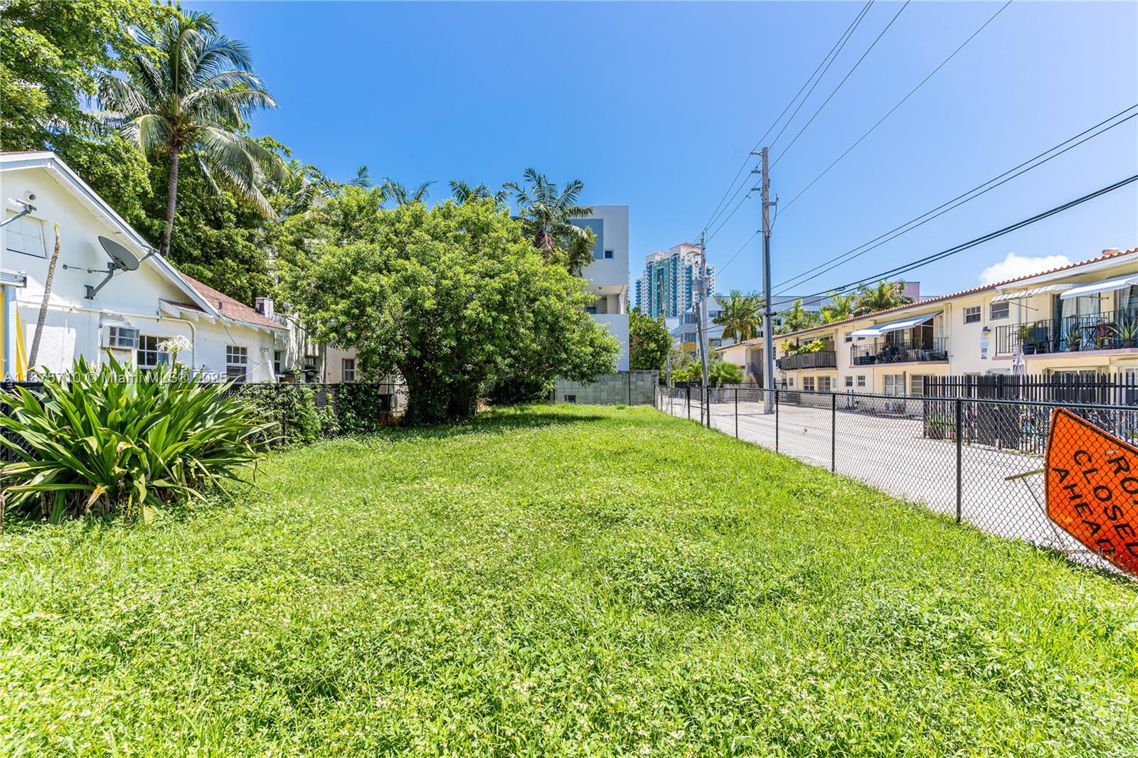 A vacant, grass-covered lot is situated between two residential buildings under a clear blue sky — 918 4th St, Miami Beach FL 33139, MIAMI BEACH, FL