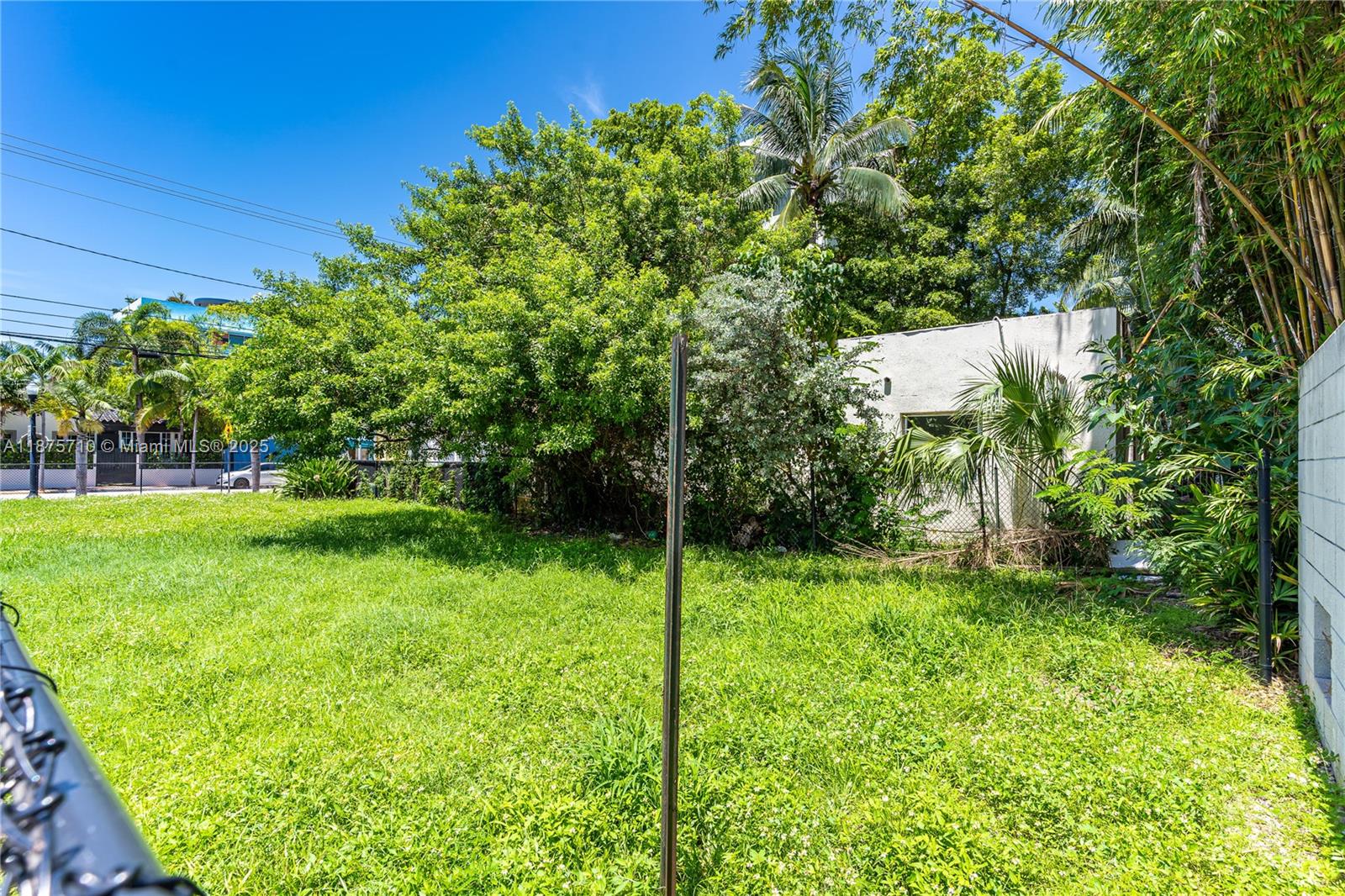 A grassy backyard features a small white building, lush trees, and a chain-link fence — 918 4th St, Miami Beach FL 33139, MIAMI BEACH, FL