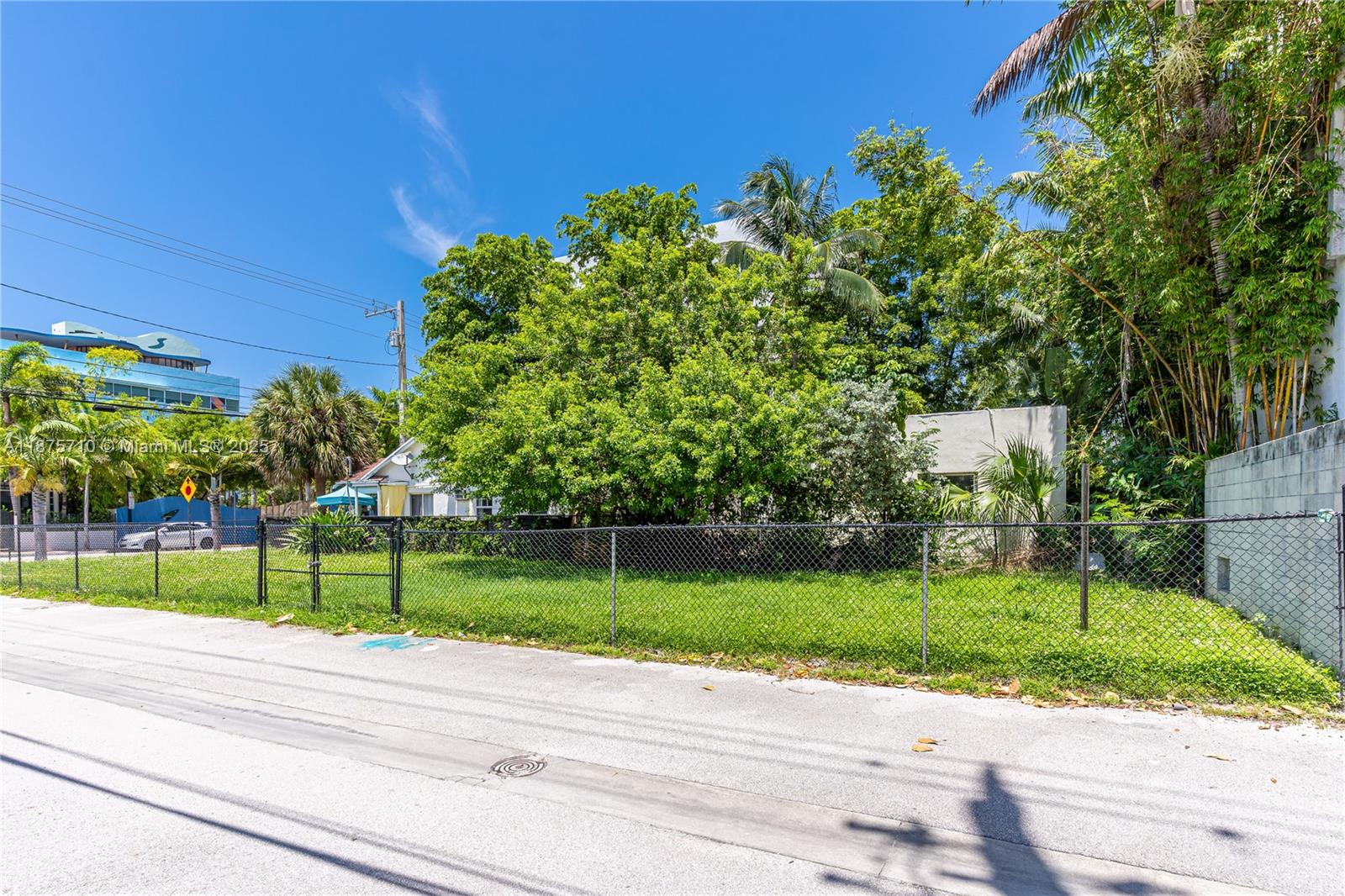 A chain-link fence encloses a grassy lot with mature trees and a small building — 918 4th St, Miami Beach FL 33139, MIAMI BEACH, FL