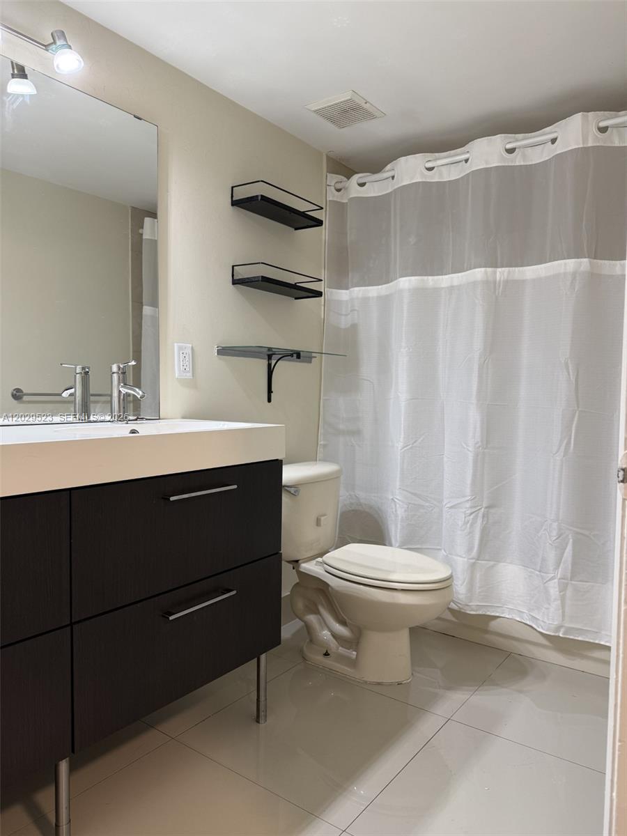 A bathroom features a dark wood vanity, a toilet, and a shower with a curtain — 8225 Lake Dr # 107, Doral FL 33166, DORAL, FL