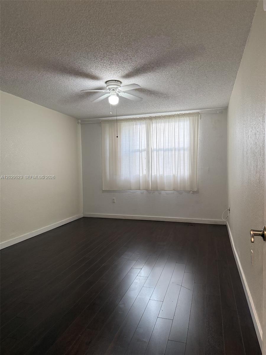 An empty bedroom features dark wood flooring, white walls, and a ceiling fan — 8225 Lake Dr # 107, Doral FL 33166, DORAL, FL