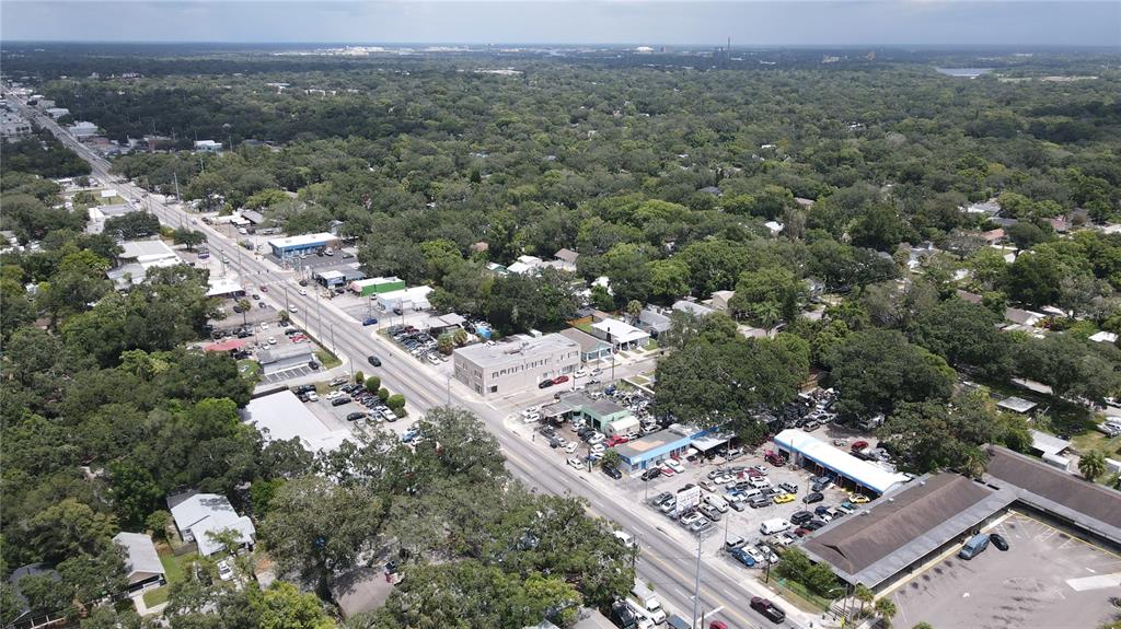 An aerial view shows a commercial street with businesses, parking lots, and surrounding residential trees — 7279 N NEBRASKA AVENUE, TAMPA, FL