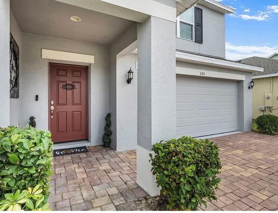 A gray house exterior features a red front door, a garage, and a paved driveway — 535 DARSHIRE AVENUE, EUSTIS, FL