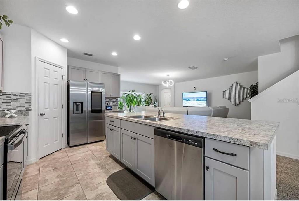 A kitchen with light gray cabinets, granite countertops, stainless steel appliances, and tile flooring — 535 DARSHIRE AVENUE, EUSTIS, FL