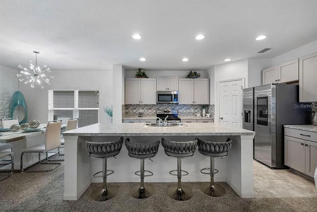 A kitchen with a central island, four bar stools, stainless steel appliances, and light cabinetry — 535 DARSHIRE AVENUE, EUSTIS, FL