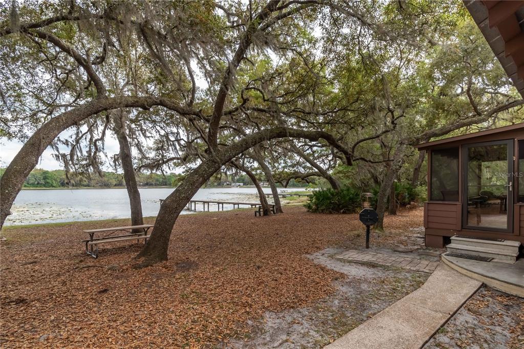 A yard with large oak trees, a picnic table, and a dock overlooking a lake — 22645 NE 105TH AVENUE ROAD, FORT MC COY, FL