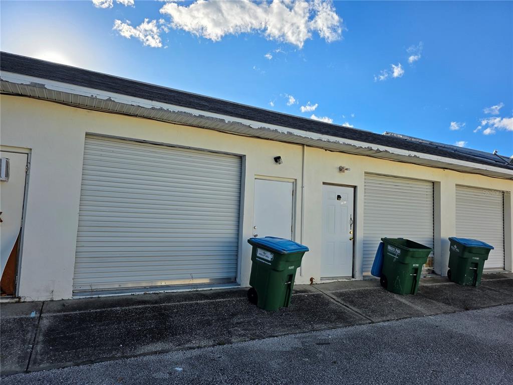 An exterior view of a commercial building with three roll-up doors and two entry doors — 787 CENTER STREET UNIT H, HOLLY HILL, FL