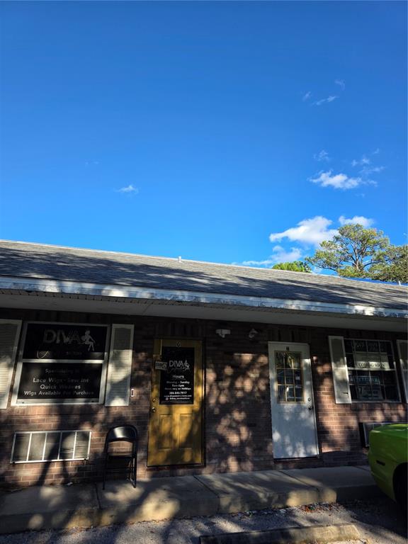 A brick commercial building exterior with two doors and a sign for a wig shop — 787 CENTER STREET UNIT H, HOLLY HILL, FL