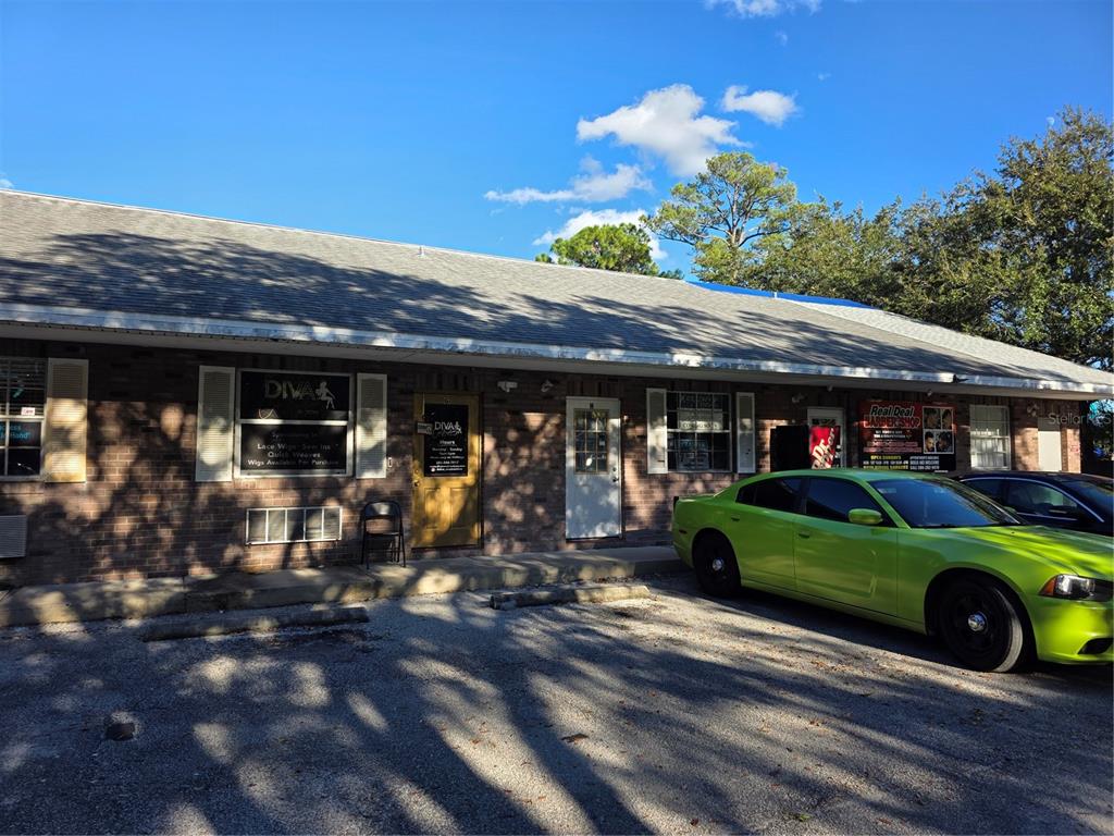 A brick commercial building with a parking lot and a bright green car in front — 787 CENTER STREET UNIT H, HOLLY HILL, FL