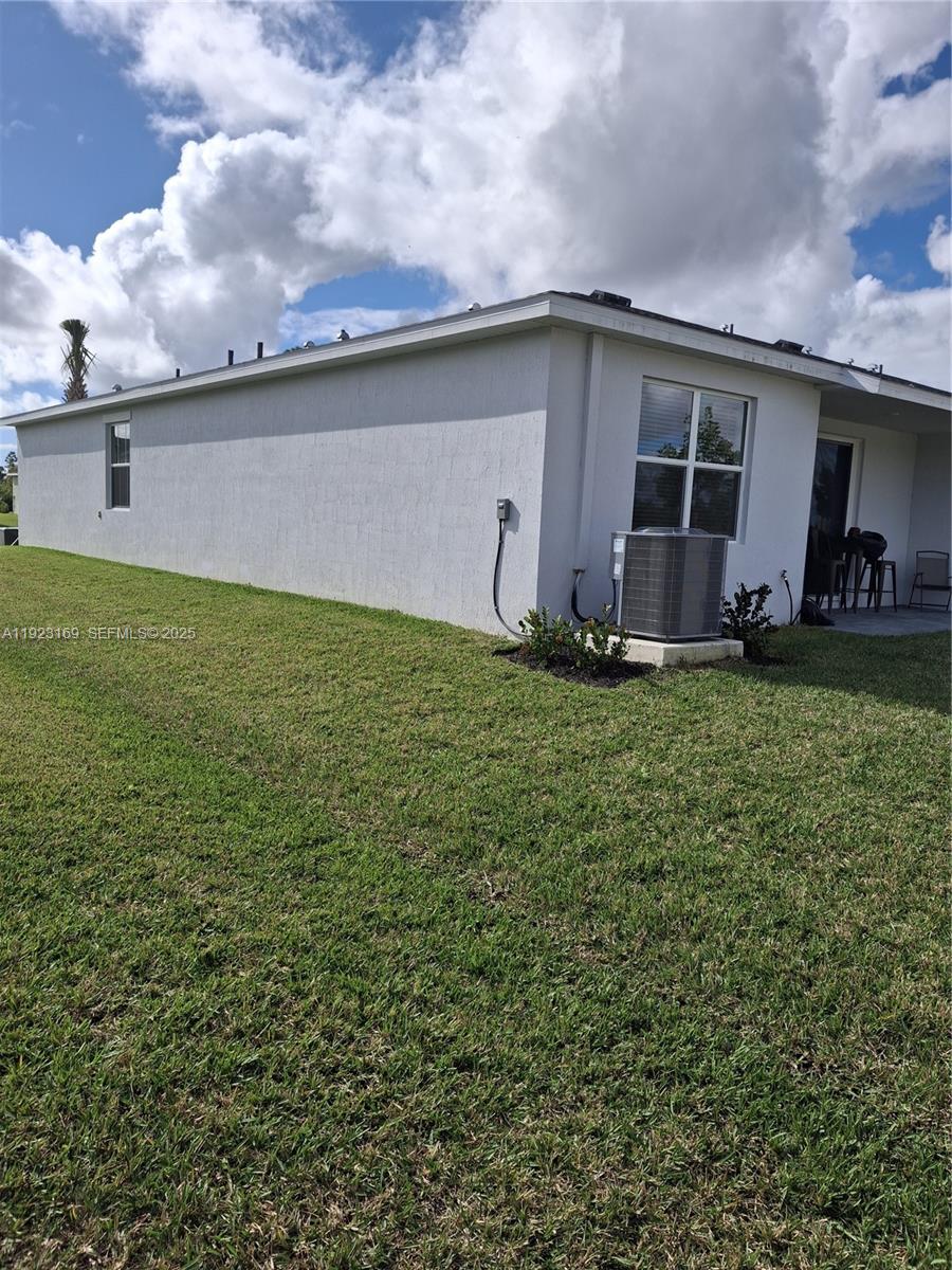 The exterior of a single-story house features a light-colored stucco wall and an air conditioning unit — 1887 Cerulean Dr, Palm Bay FL 32907, PALM BAY, FL