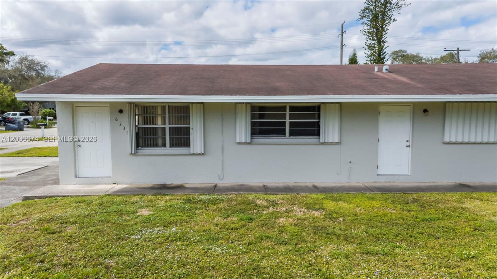 The exterior of a single-story gray building features two white doors and two windows — 6331 Pierce St # 1, Hollywood FL 33024, HOLLYWOOD, FL