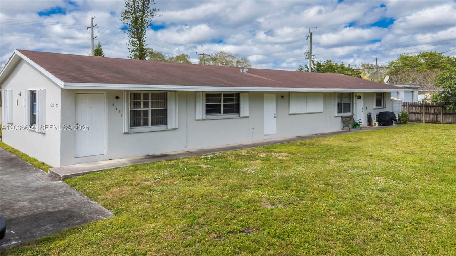 A single-story, light-colored residential building features a brown roof and a grassy front yard — 6331 Pierce St # 1, Hollywood FL 33024, HOLLYWOOD, FL