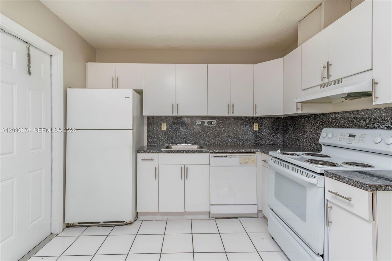 A kitchen features white cabinets, white appliances, and a dark speckled countertop with tile flooring — 6331 Pierce St # 1, Hollywood FL 33024, HOLLYWOOD, FL