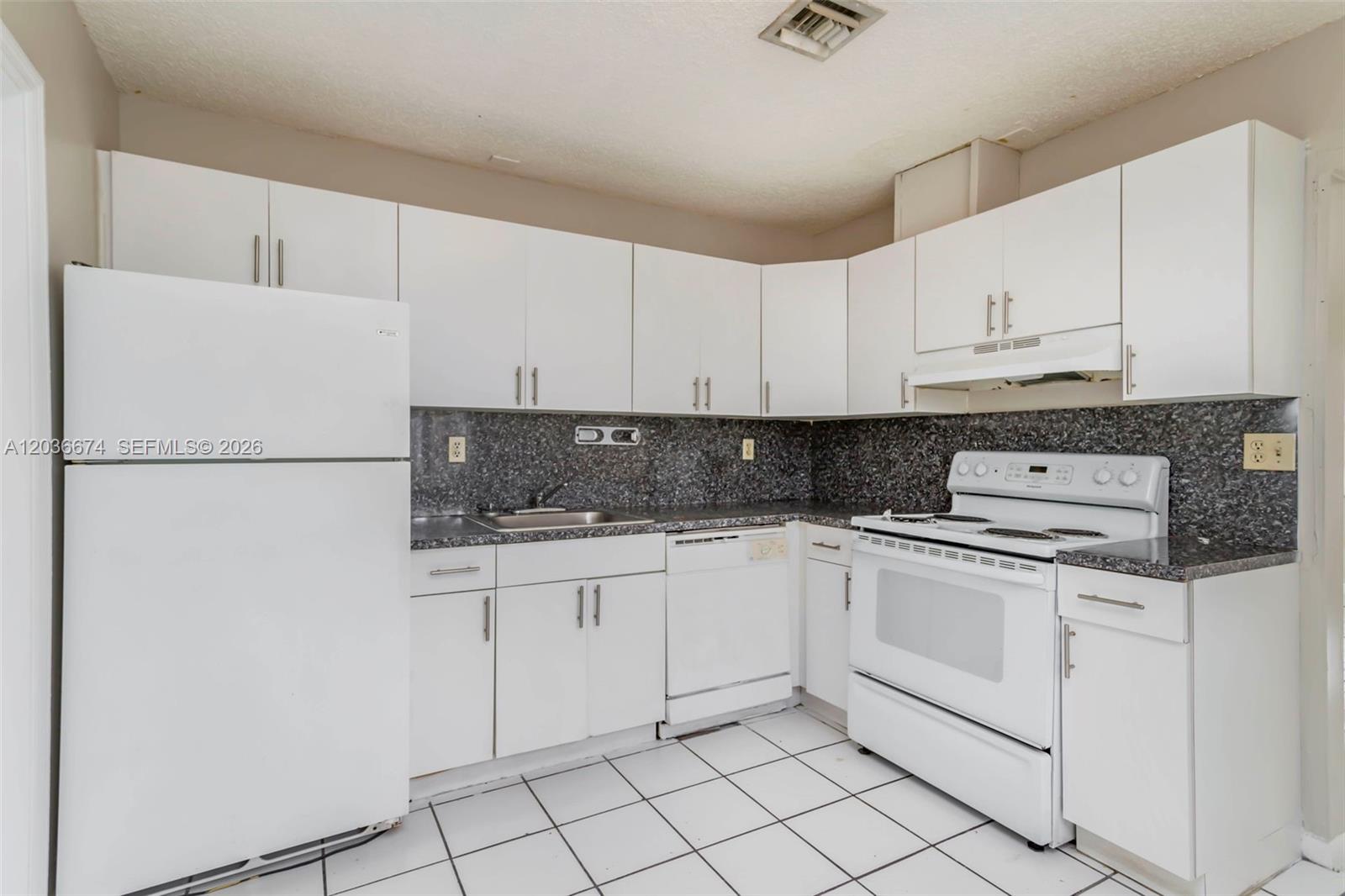 A kitchen features white cabinets, white appliances, and a dark speckled countertop — 6331 Pierce St # 1, Hollywood FL 33024, HOLLYWOOD, FL