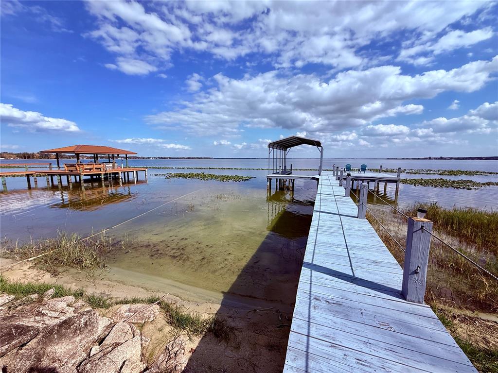A concrete patio runs along the side of a house next to a chain-link fence — 148 N LAKE REEDY BOULEVARD, FROSTPROOF, FL