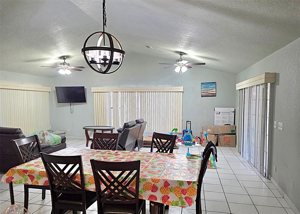 A dining area with a pineapple-patterned tablecloth, tile flooring, ceiling fans, and a pendant light — 5419 SW 84TH PLACE, OCALA, FL