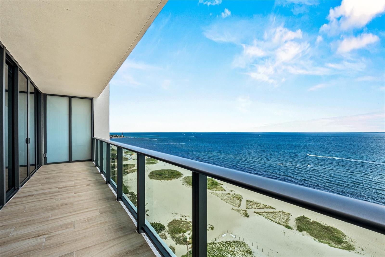 A modern balcony with wood-look tile flooring overlooks a sandy beach and the ocean — 900 N Ocean Boulevard # 1604, Pompano Beach FL 33062, POMPANO BEACH, FL