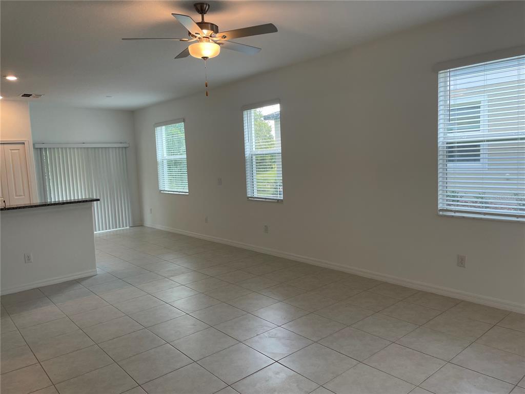 An open-concept living area features light tile flooring, a ceiling fan, and three windows — 17565 NECTAR FLUME DRIVE, LAND O LAKES, FL