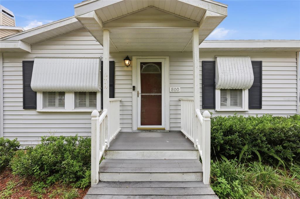 A front view of a single-story house with white siding, a covered porch, and shutters — 800 VIRGINIA AVENUE, ST CLOUD, FL