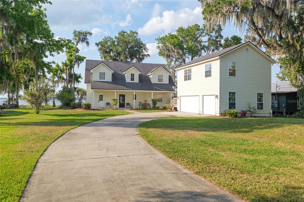 A two-story house with light yellow siding, a covered front porch, and a detached garage — 2499 SE 30TH STREET, MELROSE, FL