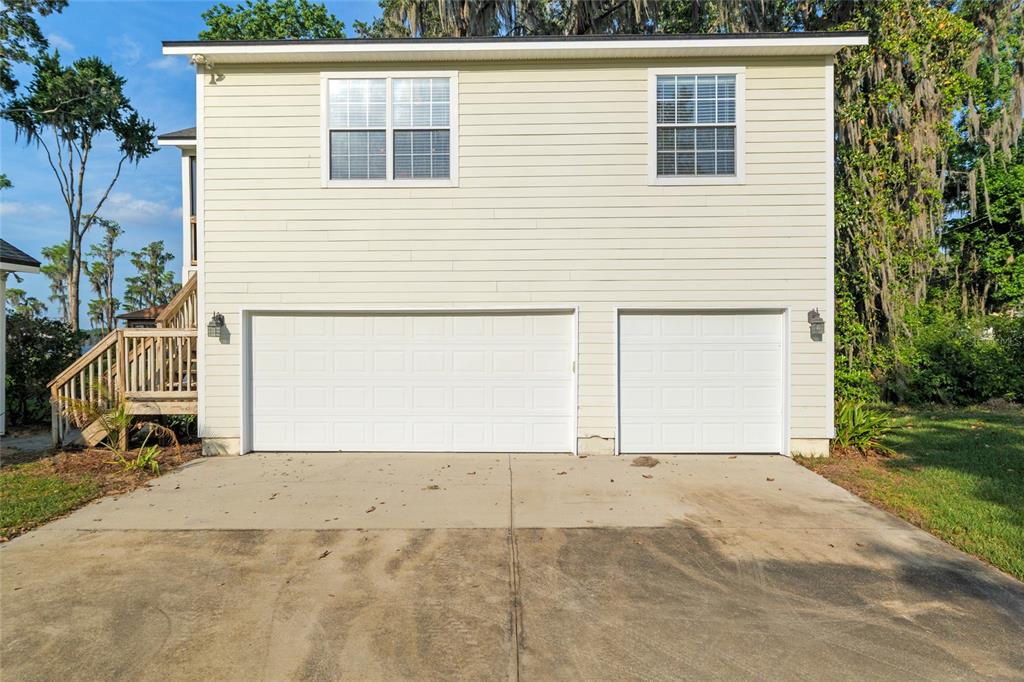 A two-story house with a two-car garage and a wooden staircase on the left — 2499 SE 30TH STREET, MELROSE, FL