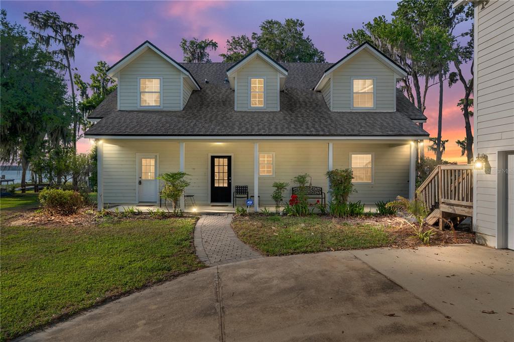 A two-story house with light siding, a covered porch, and a brick walkway at dusk — 2499 SE 30TH STREET, MELROSE, FL