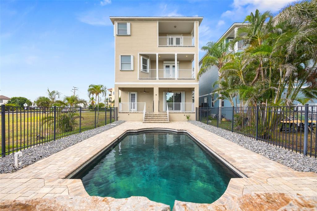A three-story house with stacked balconies overlooks a rectangular swimming pool and fenced yard — 1340 APOLLO BEACH BOULEVARD S, APOLLO BEACH, FL