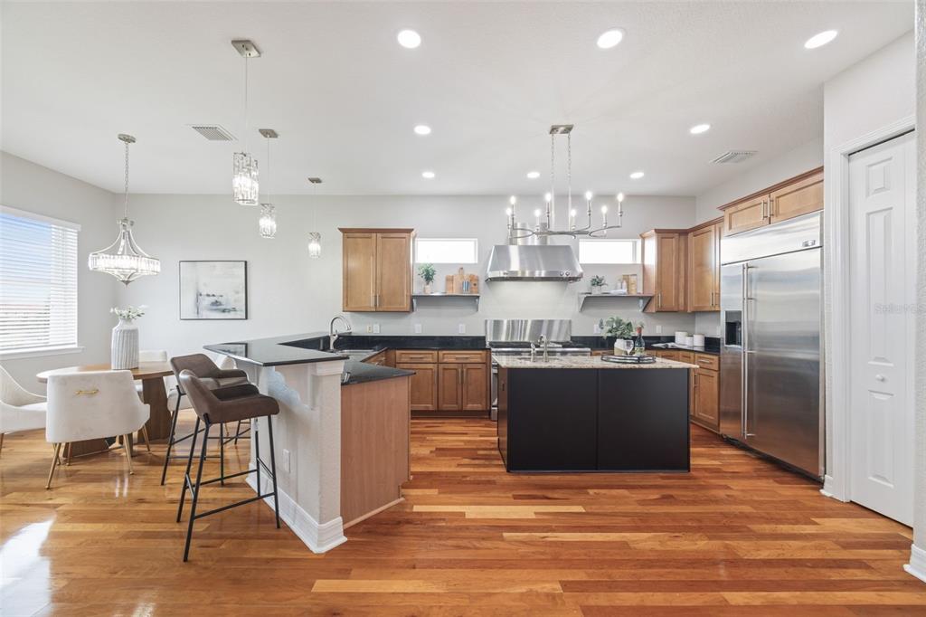 A kitchen with wood cabinets, black countertops, a center island, and hardwood flooring — 1340 APOLLO BEACH BOULEVARD S, APOLLO BEACH, FL