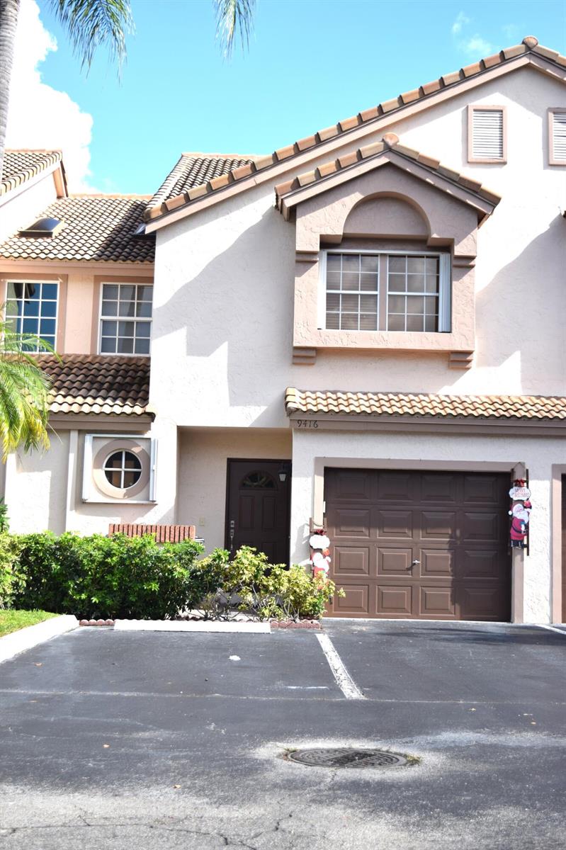 A two-story townhouse with a brown garage door, tan stucco exterior, and a tiled roof — 9416 Boca River Circle # 9416, Boca Raton FL 33434, BOCA RATON, FL