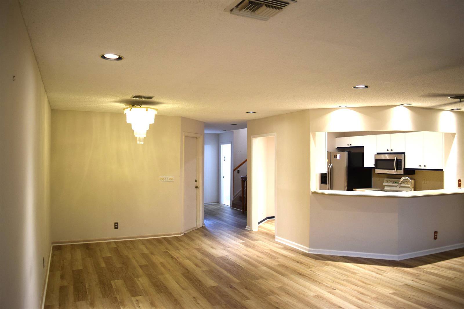 An open-concept dining area with wood-look flooring leads to a kitchen with white cabinets — 9416 Boca River Circle # 9416, Boca Raton FL 33434, BOCA RATON, FL