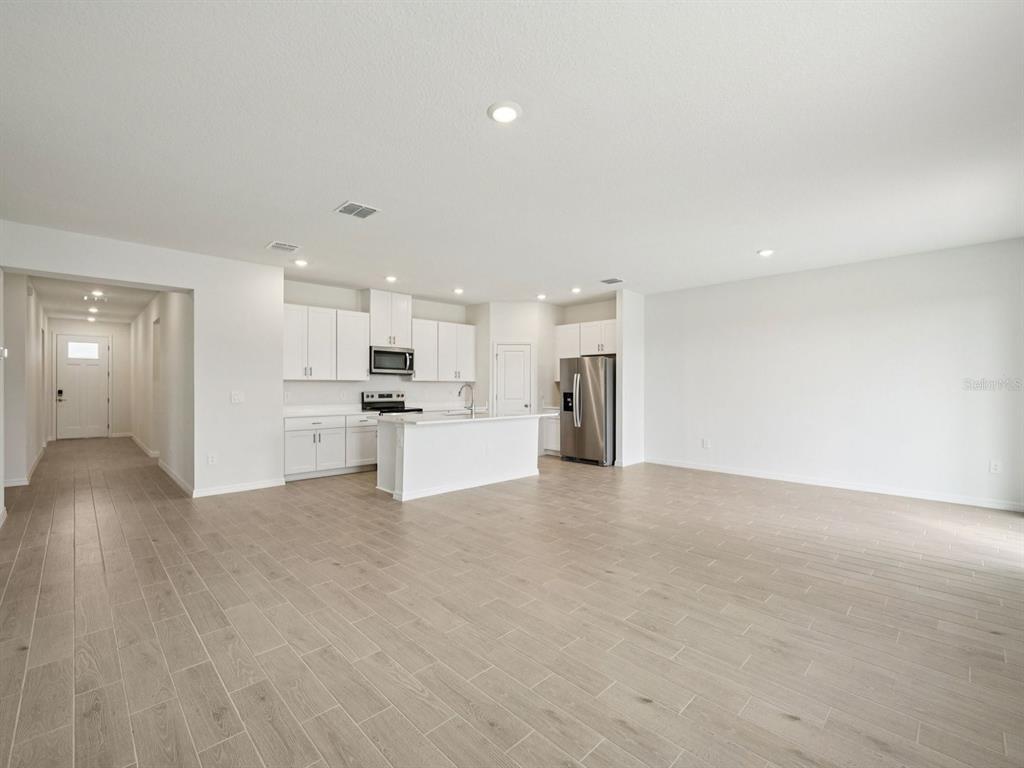 An open-concept kitchen with white cabinetry and an island overlooks a large, tiled living area — 128 OUTBACK HIDEAWAY AVENUE, NOKOMIS, FL