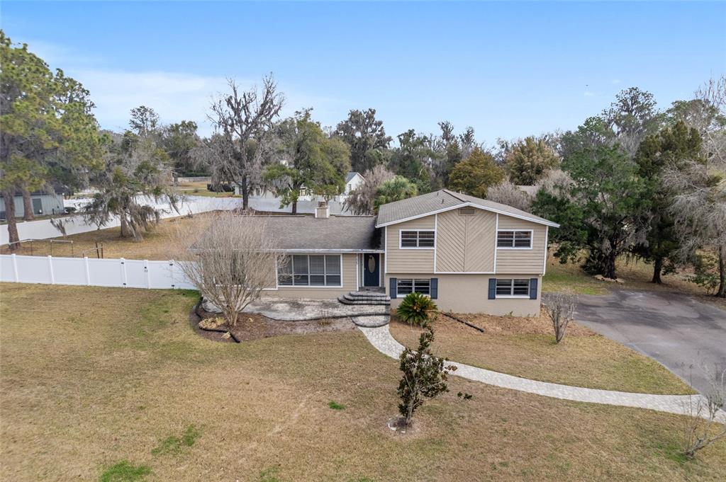 An aerial view shows a two-story house with tan siding and a white fence — 8205 SW 44TH TERRACE, GAINESVILLE, FL