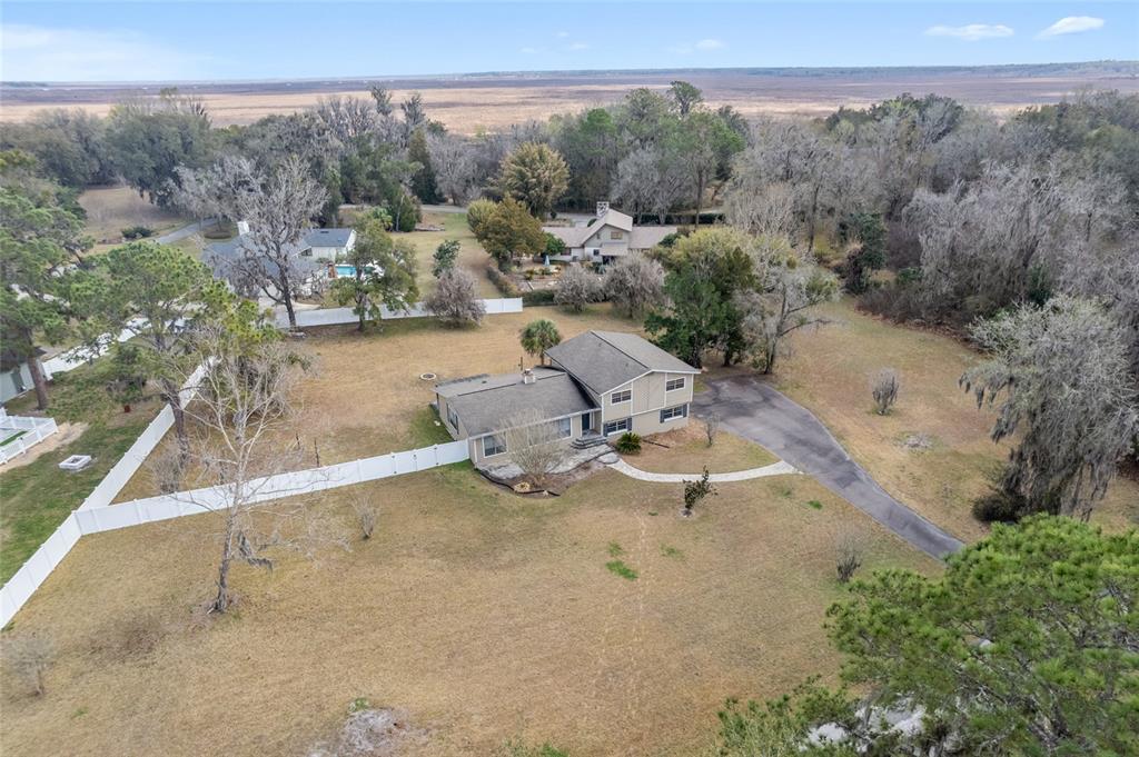 An aerial view shows a two-story house with a driveway and white fence on a lot — 8205 SW 44TH TERRACE, GAINESVILLE, FL