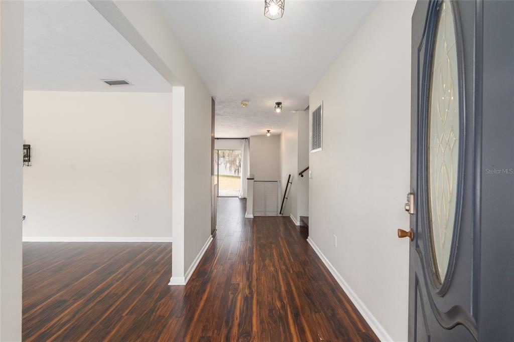 A view from an entryway into a hallway with wood-look flooring and a sliding door — 8205 SW 44TH TERRACE, GAINESVILLE, FL