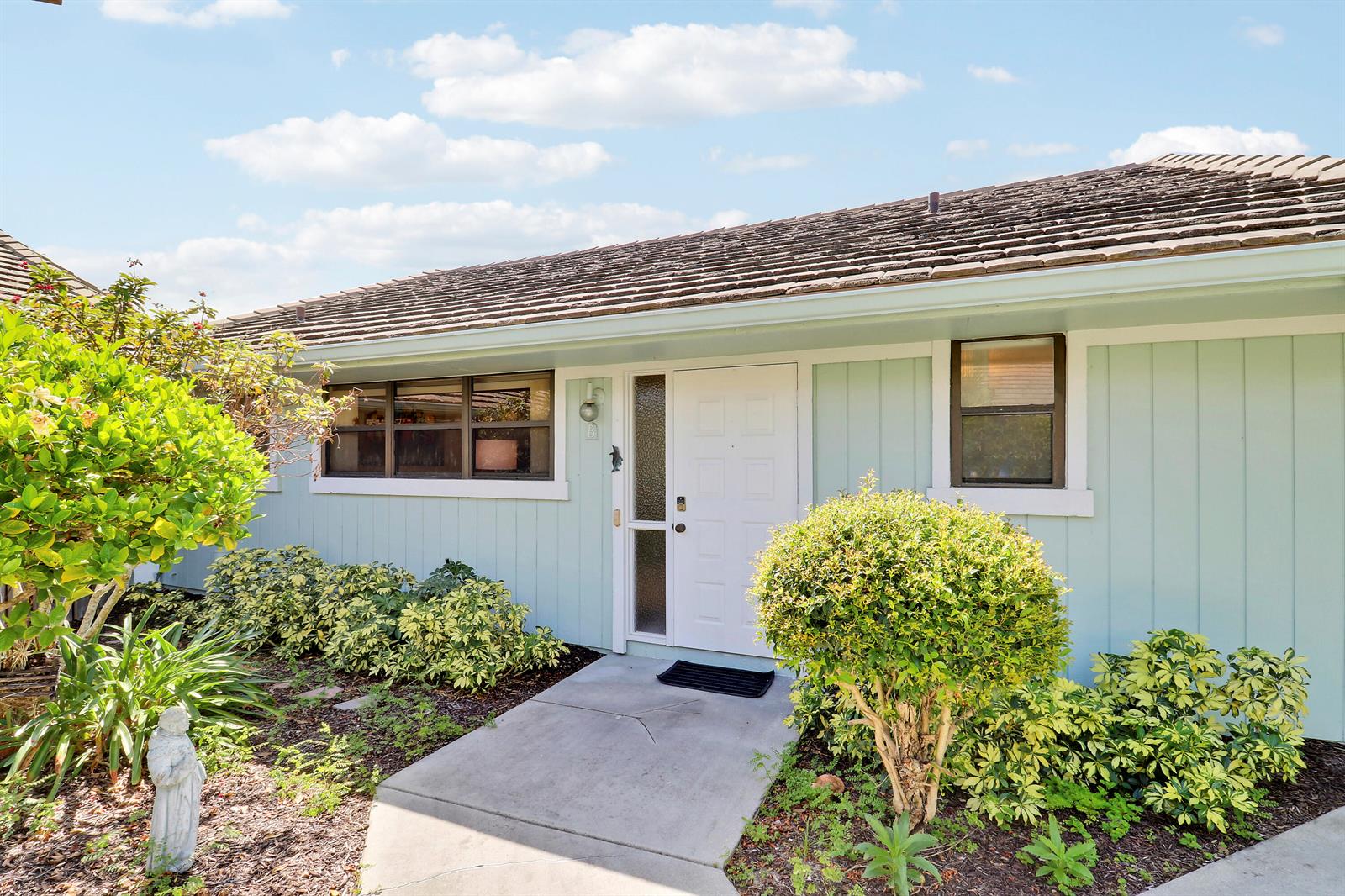 A light blue single-story house features a white front door and a concrete walkway — 1127 E Seminole Avenue # 15b, Jupiter FL 33477, JUPITER, FL