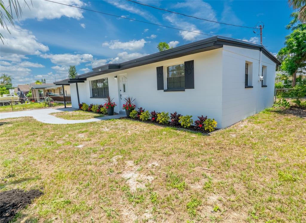 A white, single-story house with a dark roof and shutters sits on a grassy lot — 4112 W FAIRVIEW HEIGHTS, TAMPA, FL