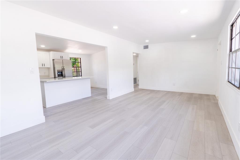 A bright living room with light wood flooring opens into a kitchen with white cabinets — 4112 W FAIRVIEW HEIGHTS, TAMPA, FL
