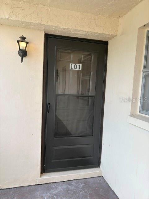 A dark-framed storm door with the number 101 is mounted on a beige exterior wall — 5521 BAY BOULEVARD UNIT 101, PORT RICHEY, FL